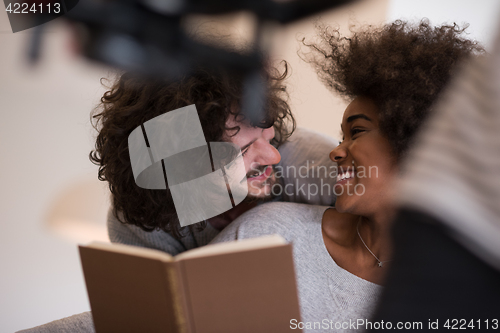 Image of multiethnic couple hugging in front of fireplace