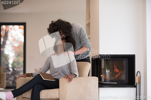 Image of multiethnic couple hugging in front of fireplace