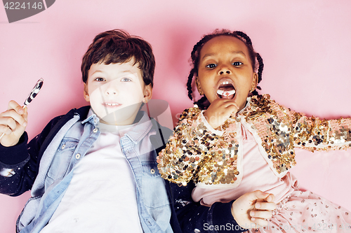 Image of lifestyle people concept: diverse nation children playing together, caucasian boy with african little girl holding candy happy smiling 