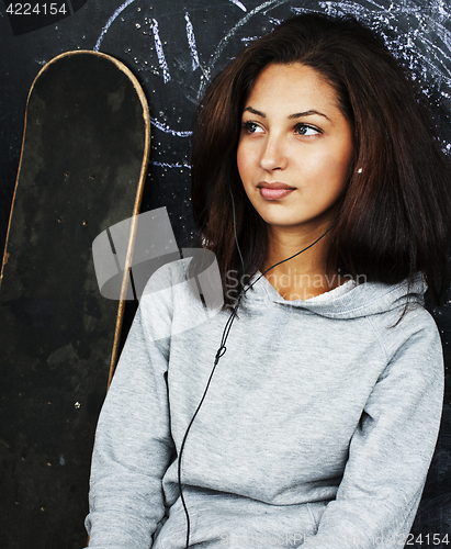 Image of young cute teenage girl in classroom at blackboard seating on ta