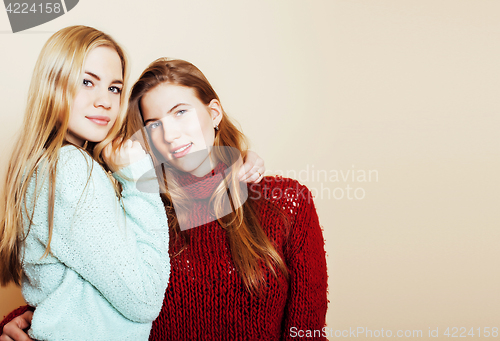 Image of Two young girlfriends in winter sweaters indoors having fun. Lif