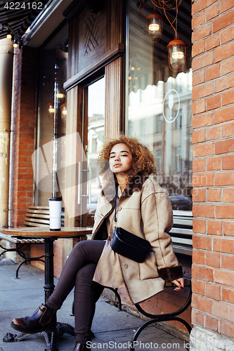 Image of young pretty african american women drinking coffee outside in c