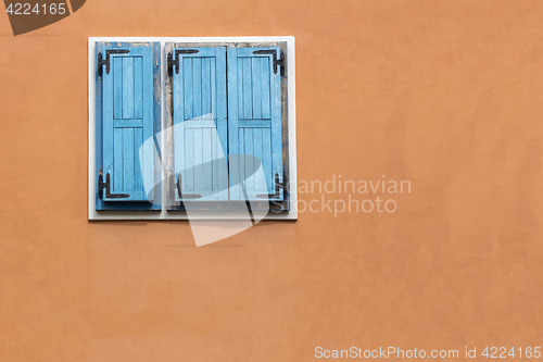 Image of Blue wooden window shutters on the orange facade