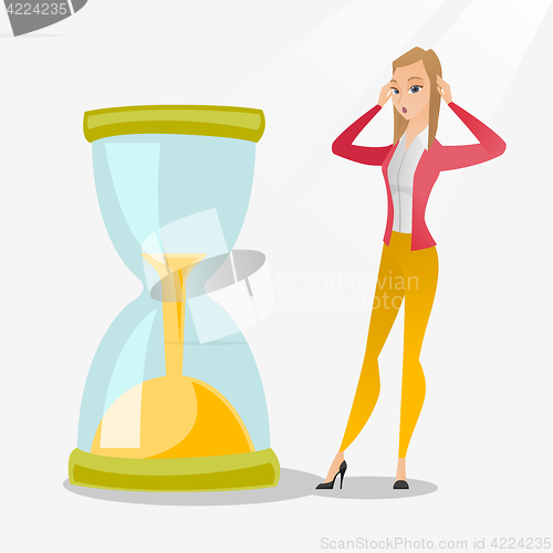 Image of Desperate business woman looking at hourglass.