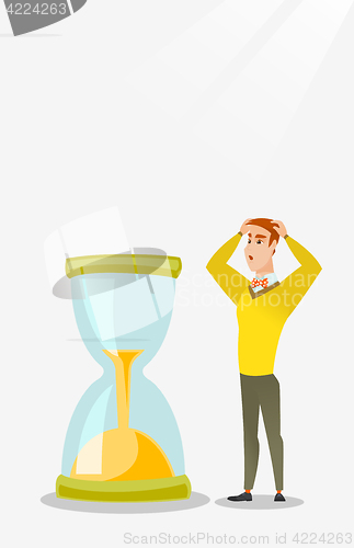 Image of Desperate businessman looking at hourglass.