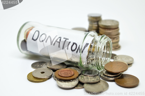 Image of Donation lable in a glass jar with coins spilling out 