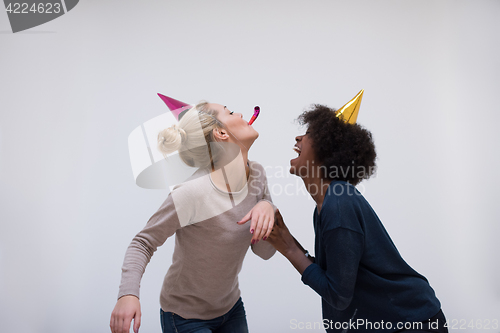 Image of smiling women in party caps blowing to whistles