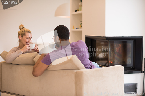 Image of Young multiethnic couple  in front of fireplace