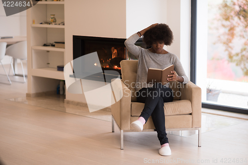 Image of black woman at home reading book