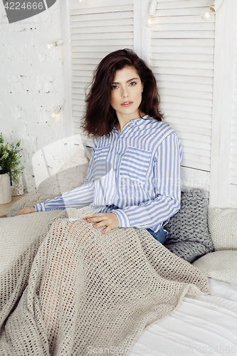 Image of young pretty brunette woman in her bedroom sitting at window, happy smiling lifestyle people concept 