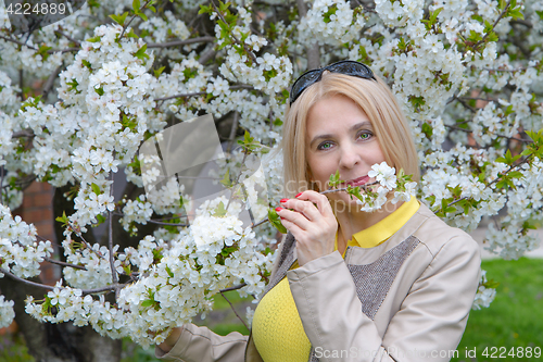 Image of The blonde sniffs a flower