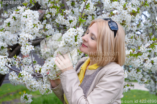 Image of The blonde sniffs a flower