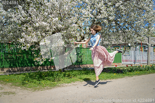 Image of Young girl on the background of a blossoming cherry tree