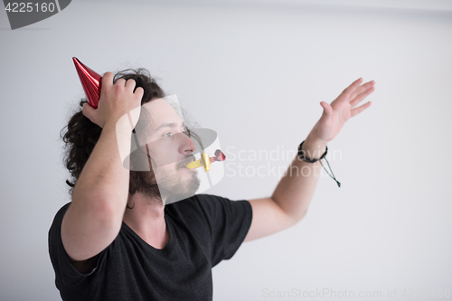 Image of Portrait of a man in party hat blowing in whistle