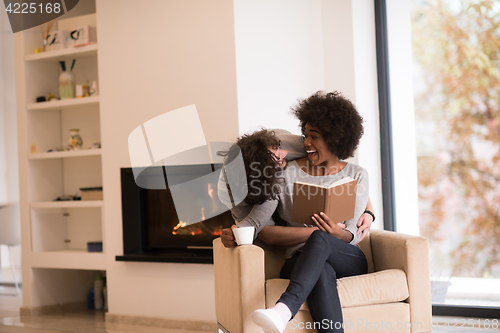 Image of multiethnic couple hugging in front of fireplace