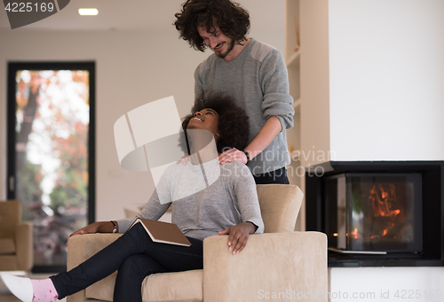 Image of multiethnic couple hugging in front of fireplace