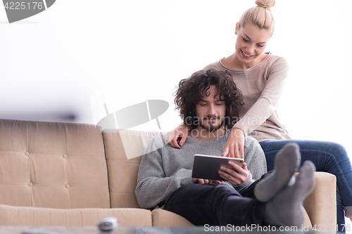 Image of couple relaxing at  home with tablet computers