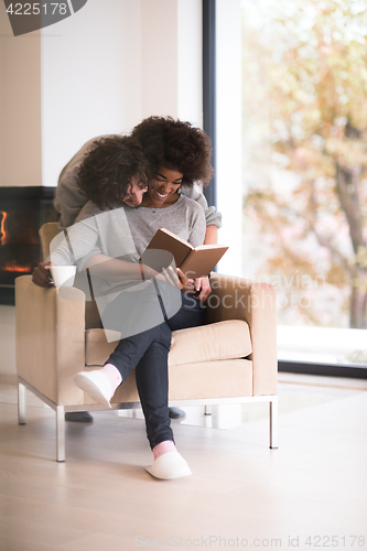 Image of multiethnic couple hugging in front of fireplace