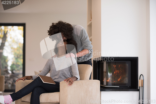 Image of multiethnic couple hugging in front of fireplace