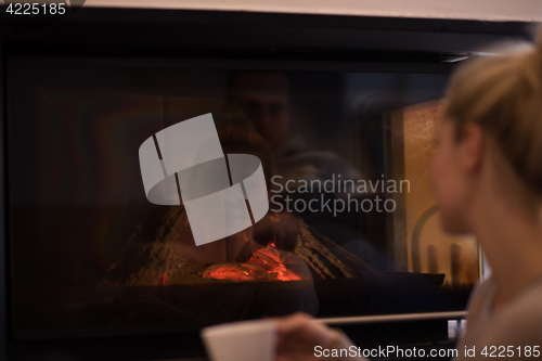 Image of young woman drinking coffee in front of fireplace