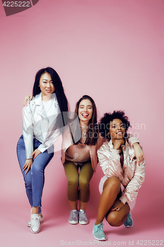 Image of three different nation girls with diversuty in skin, hair. Asian, scandinavian, african american cheerful emotional posing on pink background, woman day celebration, lifestyle people concept 