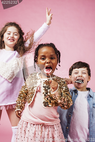 Image of lifestyle people concept: diverse nation children playing together, caucasian boy with african little girl holding candy happy smiling 