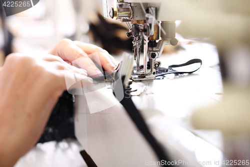 Image of Seamstress sewing on the sewing machine in the manufacturing plant 