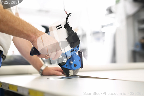 Image of Cutting room. Knife, table punching fabric. Cutting the fabric, sewing work.