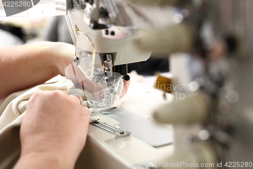 Image of Sewing. Seamstress on the machine. Production of clothes, sewing on a machine