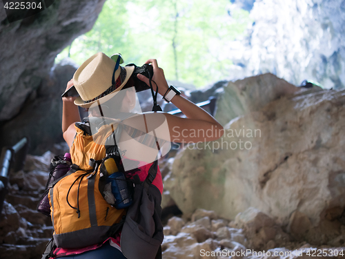 Image of Brunette with camera among rocks