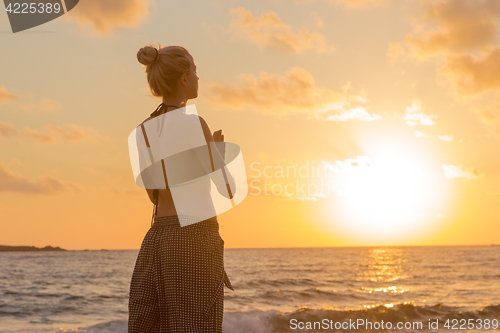 Image of Woman practicing yoga on sea beach at sunset.