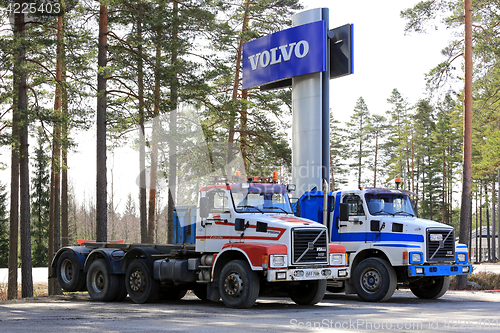 Image of Two Conventional Volvo N12 Trucks under Volvo Sign