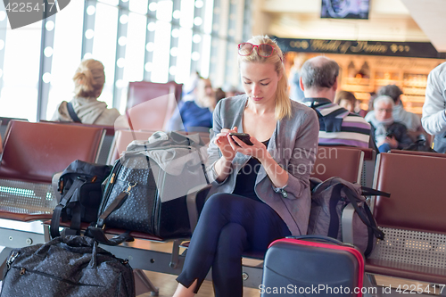 Image of Female traveler using cell phone while waiting on airport.