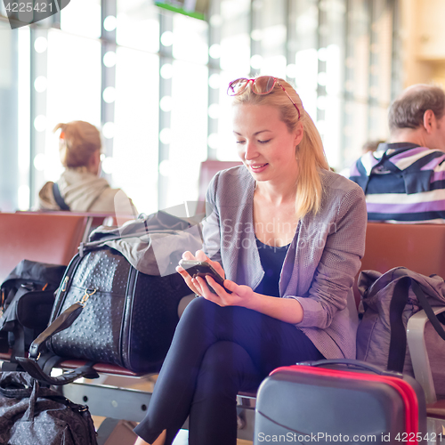 Image of Female traveler using cell phone while waiting on airport.