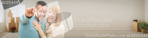 Image of Young Adult Couple Inside Room with Boxes Holding New House Keys