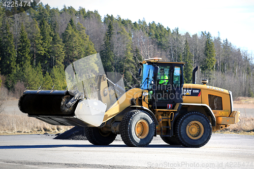 Image of Cat Wheel Loader Bucket Sweeper Cleans Yard at Spring 