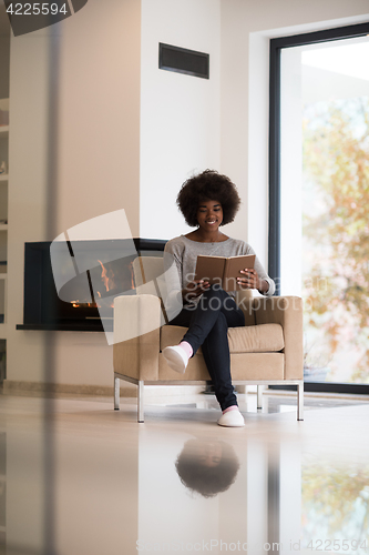 Image of black woman at home reading book