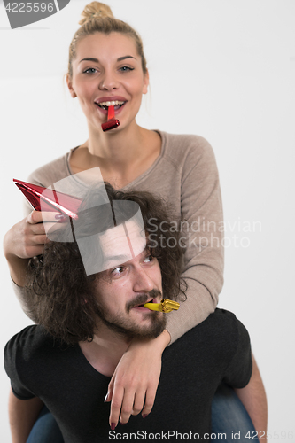 Image of couple in party hats blowing in whistle