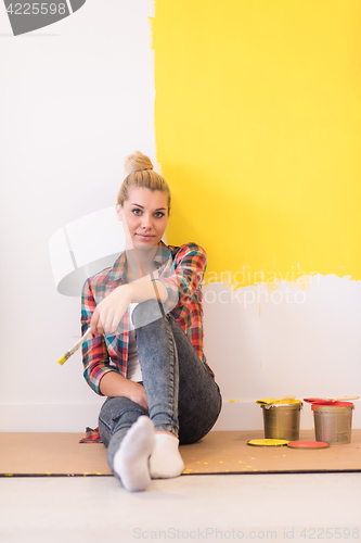 Image of young female painter sitting on floor