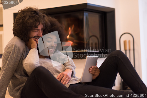 Image of multiethnic couple using tablet computer on the floor