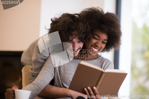 Image of multiethnic couple hugging in front of fireplace