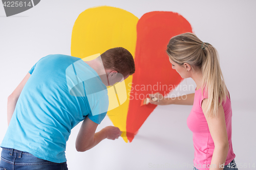 Image of couple are painting a heart on the wall