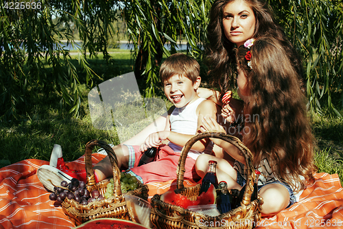 Image of cute happy family on picnic laying on green grass mother and kid