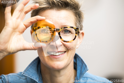 Image of woman with glasses looking through orange glass