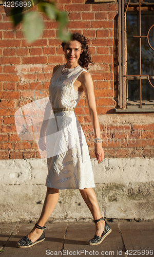Image of smiling middle-aged woman in a white dress
