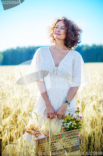 Image of smiling beautiful woman in white summer dress in a field