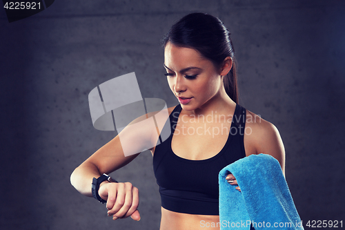 Image of young woman with heart-rate watch and towel in gym