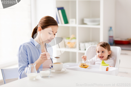 Image of happy mother and baby having breakfast at home