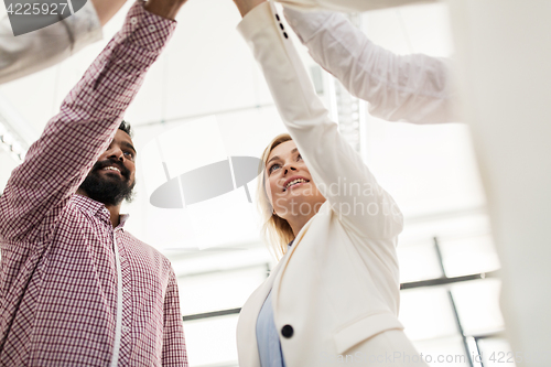 Image of happy business team making high five at office