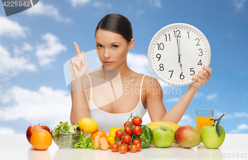 Image of woman with food and big clock sitting at table